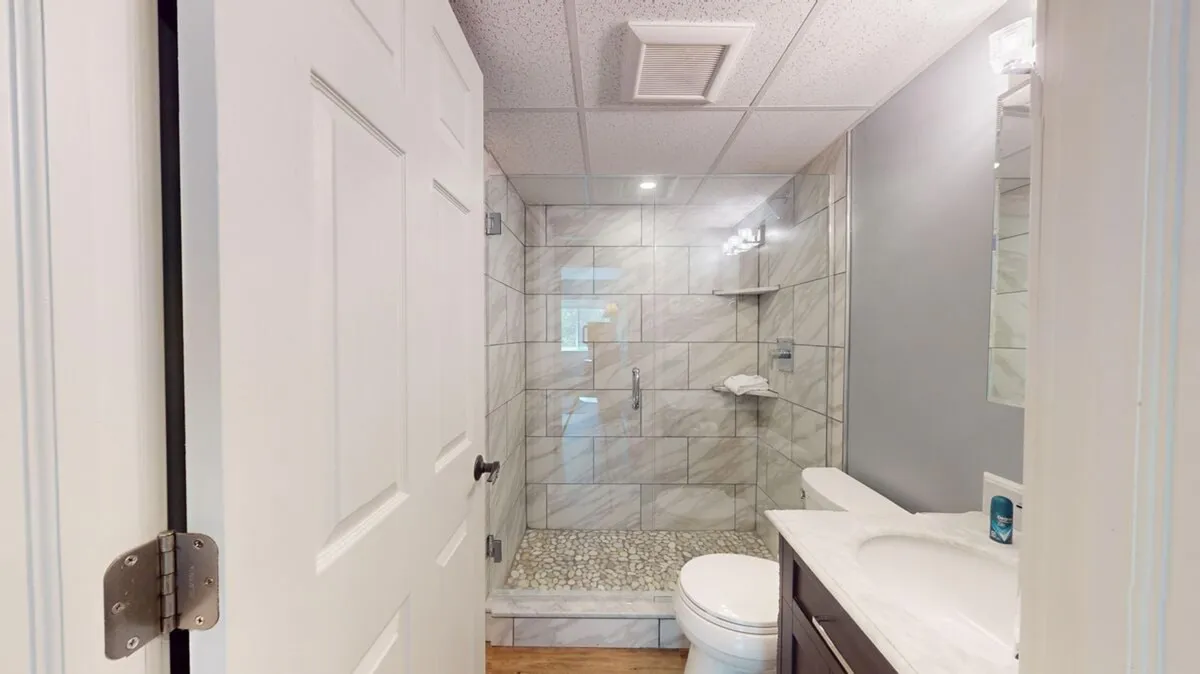 A fresh and calming bathroom scene featuring a modern shower area, sink, and mirror. The space invites personal grooming and self-care routines, evoking the sense of spa-like relaxation after a workout or swim.