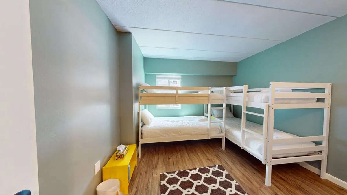 A cozy guest room with bunk beds, an area rug, and a bright window. The playful yet restful vibe makes it both family-friendly and flexible, suitable for children or extra guests.