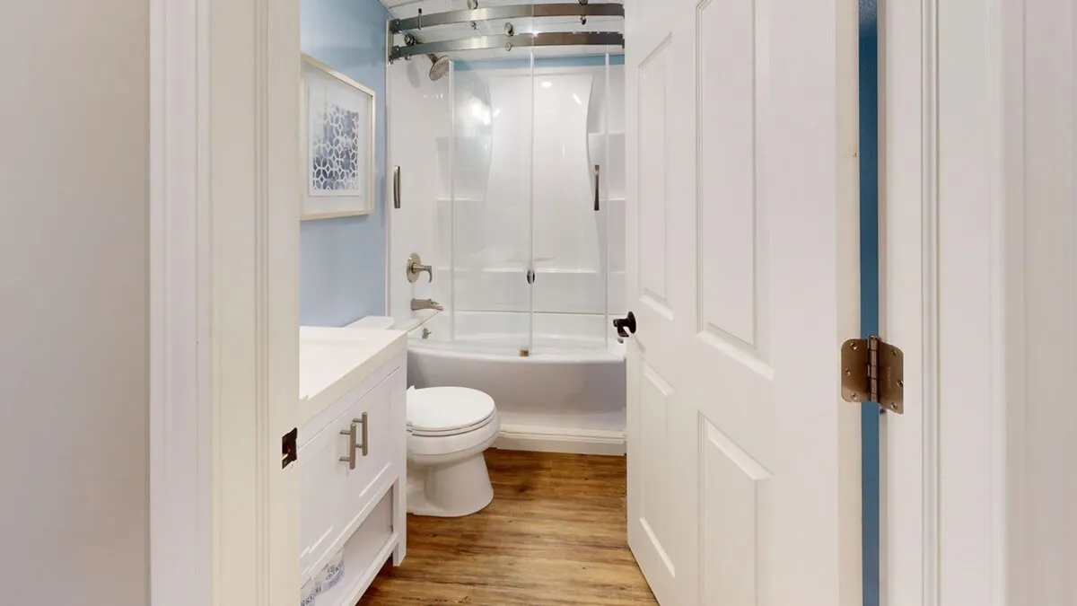 A calming bathroom scene featuring a bathtub with sliding glass doors, a white vanity, and framed artwork. The space exudes simplicity and relaxation, perfect for soaking after a day spent exploring or enjoying the resort's wellness facilities.