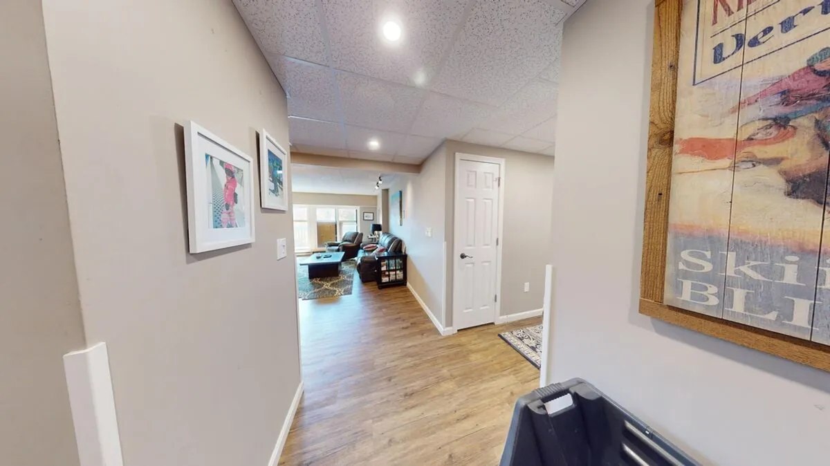 A warm, inviting living area with comfortable furnishings, framed artwork on the walls, and a door that suggests access to other rooms, likely leading toward outdoor spaces. The arrangement is ideal for family gatherings, socializing, and serves as a hub for transitioning between indoor and outdoor activities.