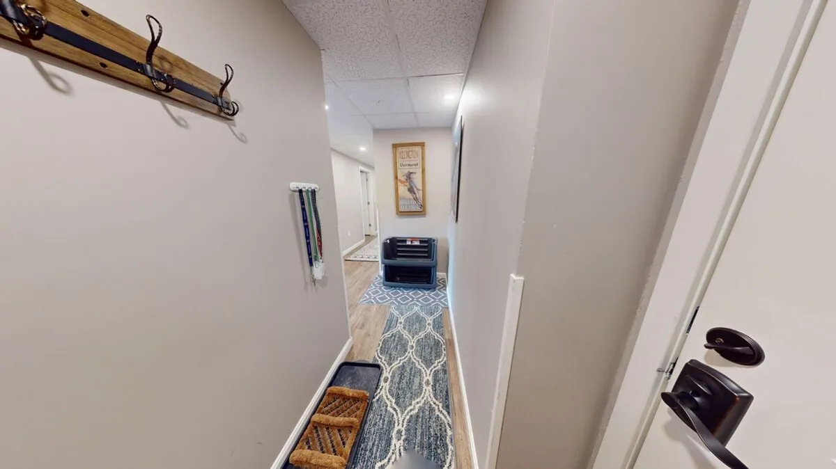 A functional entry area with a coat rack, rug, decorative wall art, and doorways leading further inside. This space conveys the transition from adventure or wellness activities back to the comfort of the condo.
